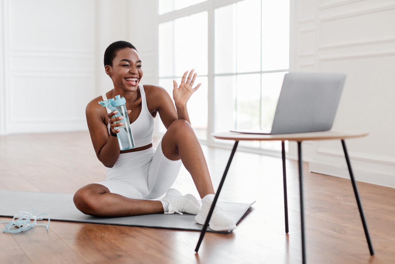 Athletic Woman Holding a Water Bottle Waiving at a Laptop